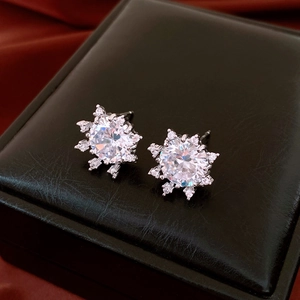 Detailed close-up of a silver snowflake earring with a round zircon center on black leather