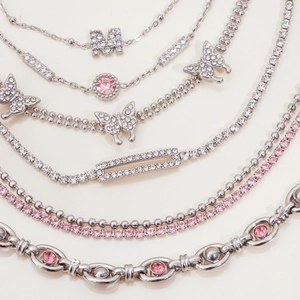 Close-up of silver-tone stainless steel multi-layer bracelet and necklace with pink stones