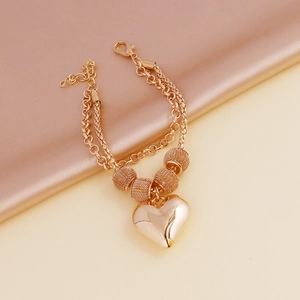 Detailed macro view of golden double-layered heart charm bracelet with round beads