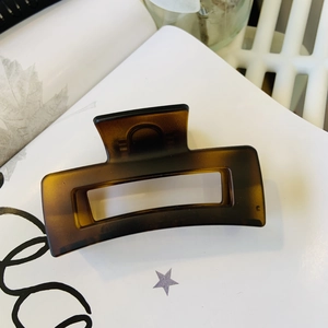 Macro detail of dark brown tortoiseshell hair claw clip with minimalist hollow rectangle design
