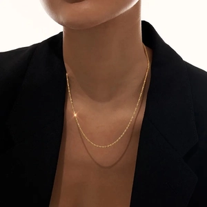 Elegante collar brillante de acero de titanio chapado en oro sobre ropa negra minimalista