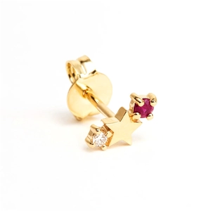 Macro shot of gold star stud earring with a red gemstone and clear crystal accent