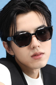 Close-up of black oversized square frame sunglasses on a model with a soft blue backdrop