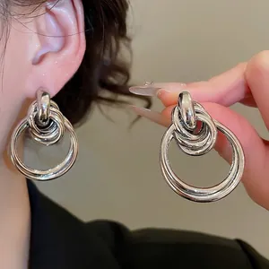 Boucles d'oreilles pendantes en métal argenté poli avec cercles noués et design minimaliste