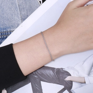 Detail showing a sleek silver stainless steel woven chain bracelet on a female wrist