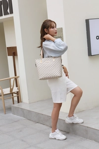 Chic beige monogram tote bag with geometric pattern shown in an outdoor street setting