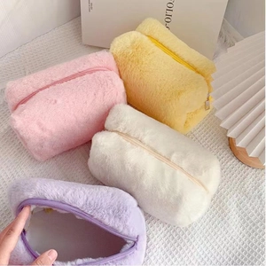 Detailed macro view of soft plush makeup bags in pastel pink, yellow, and white colors