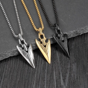 Vintage arrowhead pendant necklaces in silver, gold, and black finishes on stone background