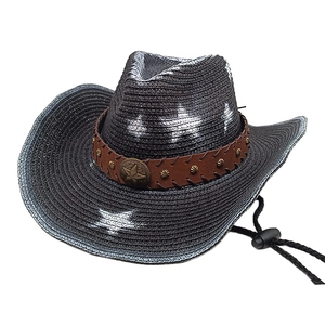 Detail of black straw cowboy hat featuring brown band with metal studs and star badge