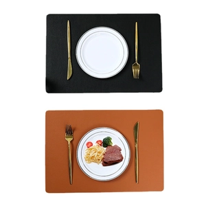Double-sided rectangular leather placemats in black and brown with cutlery and food