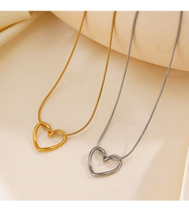 Detailed view of gold and silver heart pendants on snake chains over beige silk fabric