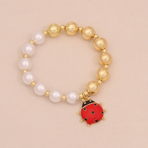 Elegant beaded bracelet with gold beads, white pearls and a red enamel ladybug charm