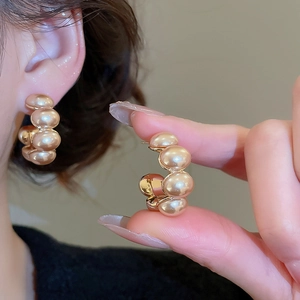 Detailed view of C-shaped champagne pearl hoop earrings with gold-plated finish