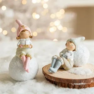 Cute resin Christmas angel girl figurines on snowballs with warm festive lighting