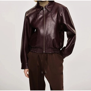 Détail de la veste en cuir bordeaux avec fermeture éclair et texture grainée premium
