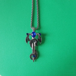 Collier avec pendentif dragon enroulé autour d'une épée et pierres bleues sur fond vert