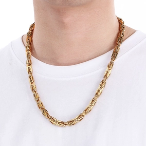 Primo piano di una pesante collana bizantina in acciaio inossidabile dorato da uomo su modello