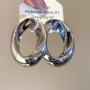 Detailed macro view of large oval metallic hoop earrings with high-polish silver finish