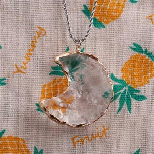 Détail d'un pendentif lune en cristal de verre facetté avec bord doré sur une chaîne en or