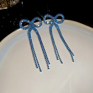 Detailed macro view of sparkling blue rhinestone bowknot drop earrings with long tassels