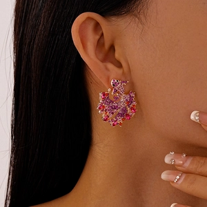 Detailed close-up of vibrant pink and purple rhinestone phoenix-shaped drop earrings