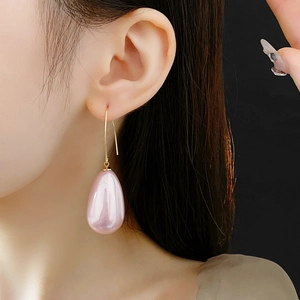 Dettaglio ravvicinato di orecchini con perle rosa a goccia indossati con ganci