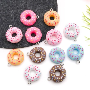 Close-up of colorful resin donut pendants with sugar sprinkles and metal loops for DIY jewelry
