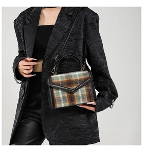 Dettaglio borsa vintage in lana a quadri con finiture in pelle nera e fibbia dorata
