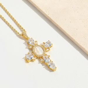 Close-up of golden cross necklace with drop zircons and Madonna center on twist chain