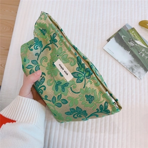 Macro detail of the green floral jacquard fabric and simple wish woven label on the pouch