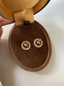 Close-up of vintage round pearl earrings with zircon halo set in a brown velvet jewelry box