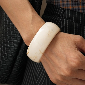 Detailed macro view of a creamy white resin bangle with brown marble texture