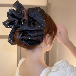 Détail d'une pince à cheveux élégante à ruban noir et pois blancs sur les cheveux
