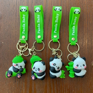 Close-up of four cute cartoon panda keychains with green silicone wristbands and gold hooks