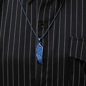 Detailed close-up of a blue titanium steel wing pendant worn on a striped shirt