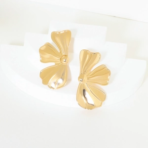 Macro detail of polished gold flower earrings with a curved petal design on white background
