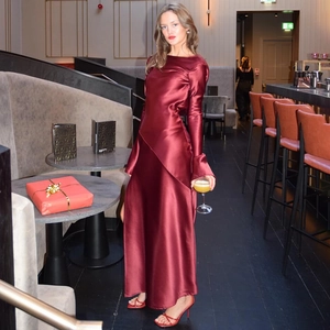 Detail of elegant burgundy satin maxi dress featuring a high slit and backless design