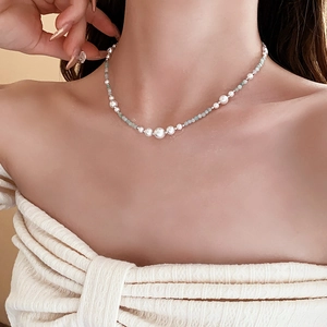 Elegante Halskette mit weißen Perlen und hellblauen Perlen am Modelhals gezeigt