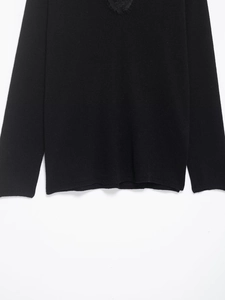 Detail of elegant black V-neck knitwear featuring delicate eyelash lace trim on neckline