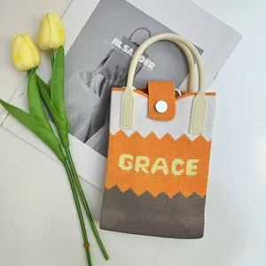 Detail of knitted tote bag featuring orange zigzag pattern and woven GRACE lettering