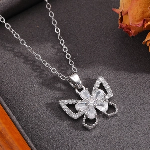 Detail of silver bow pendant necklace with sparkling crystals on grey textured fabric