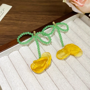 Dettaglio di orecchini con fiocco di perline verdi e petali in organza gialla