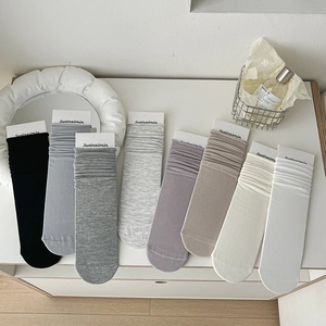 Neutral knit slouch socks with ribbed texture in multiple colors on a white desk