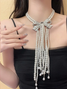 Detail of bridal pearl tassel necklace with rhinestone bow and drop pendants
