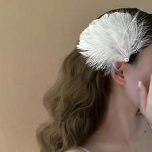 Elegant white feather hair clip with pearl detail worn by model for a retro french look