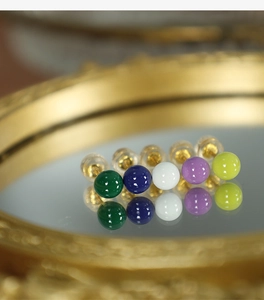 Macro view of colorful enamel mini stud earrings with gold pins and silicone backs