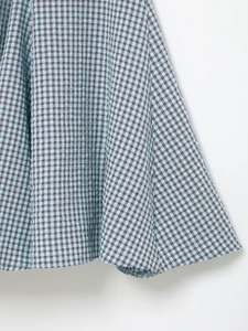 Detail view of the blue and brown gingham fabric with puckered texture and wavy hemline