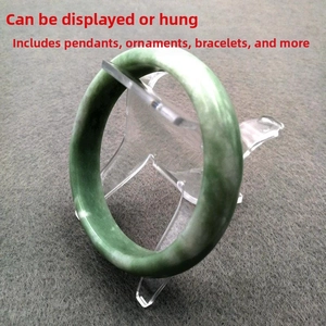 Detail of emerald green jade bracelet on clear acrylic stand over grey felt surface