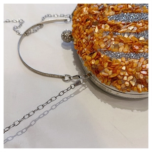 Detail of pumpkin-shaped evening clutch with orange shell fragments and silver chain