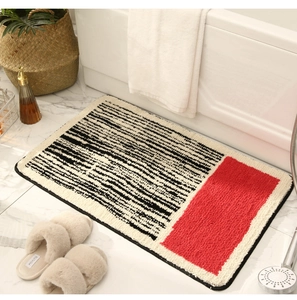 Detail of plush rectangular bath mat featuring red accent on marble tile bathroom floor
